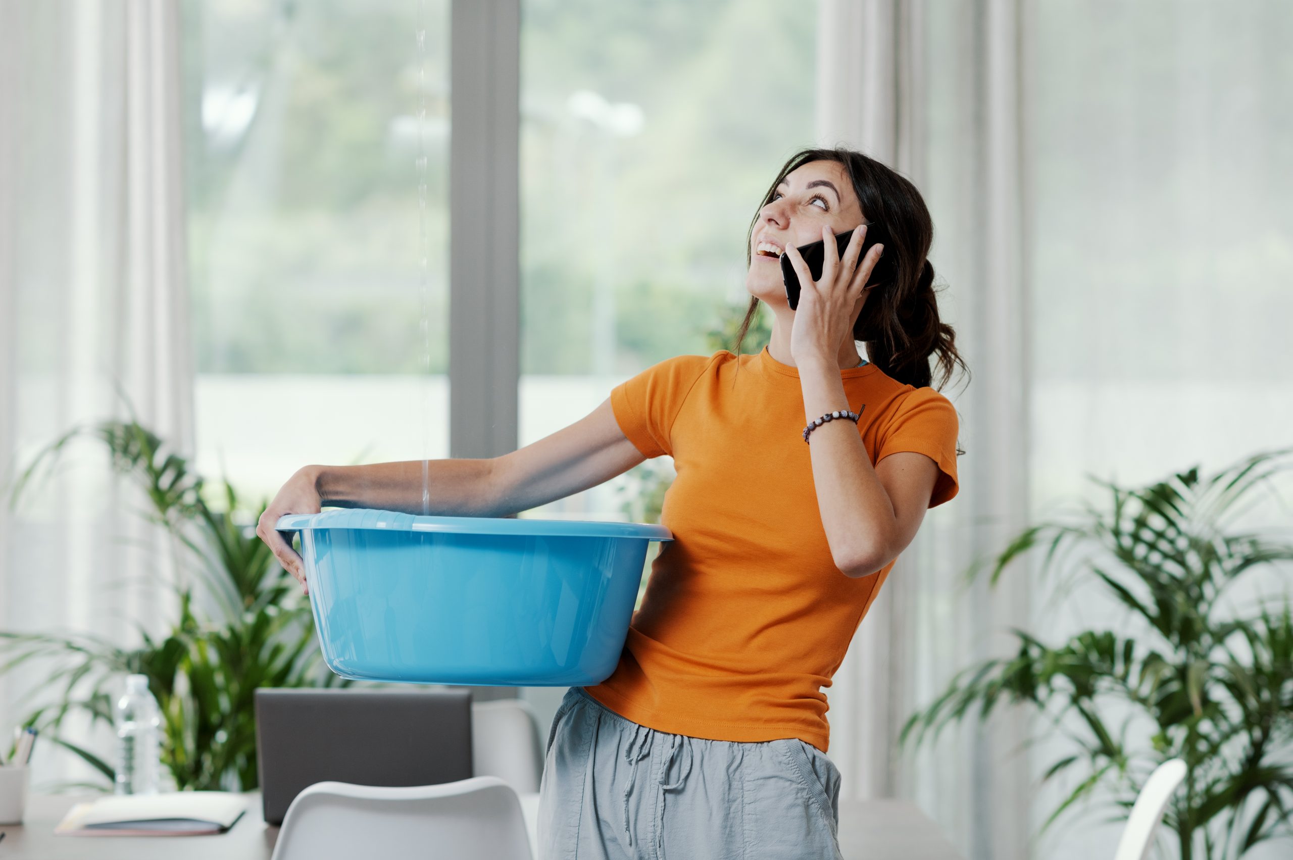 Woman collecting water leaking from the ceiling roof leak