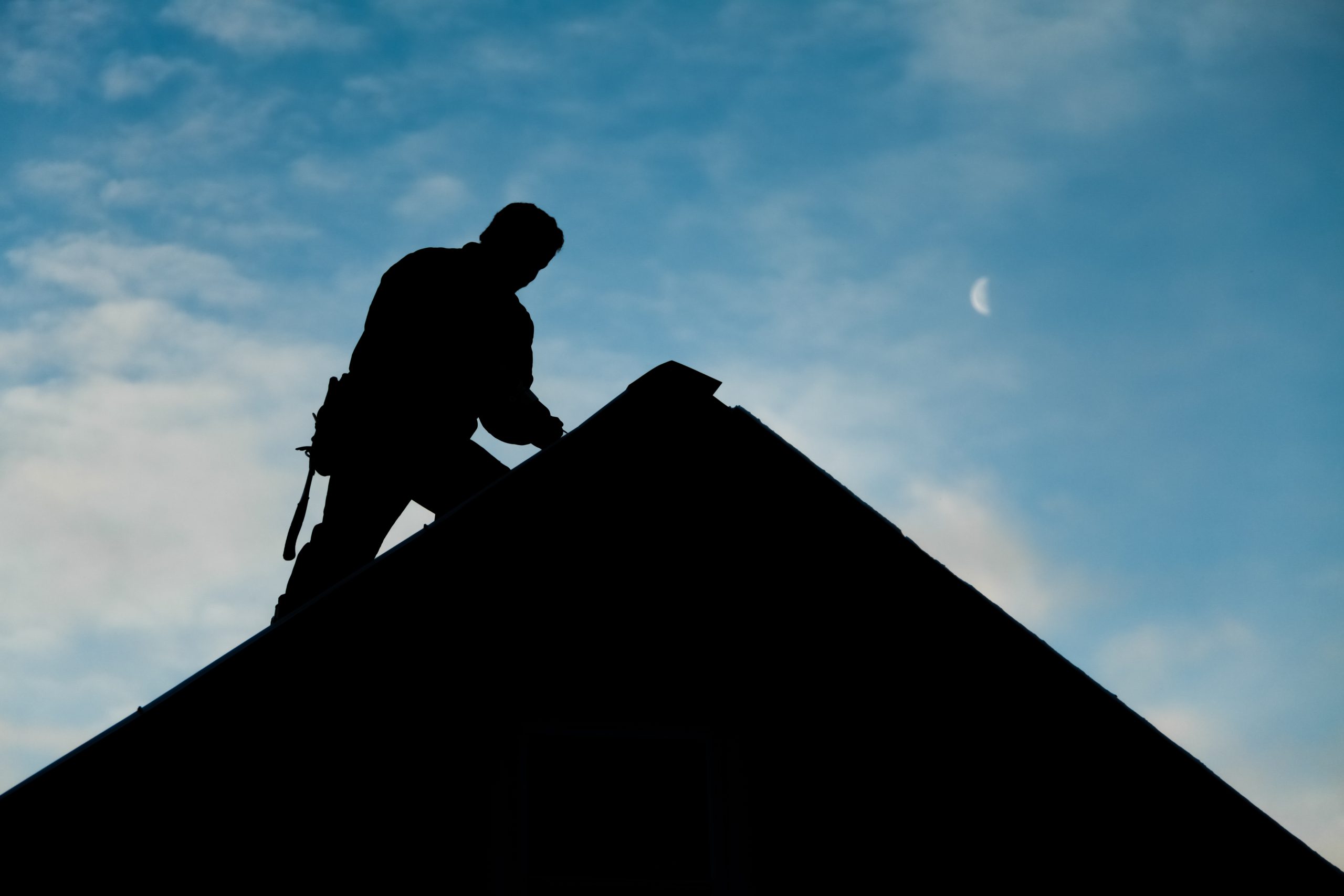 Contractor in Silhouette working on a Roof Top Factors Influencing the Cost of Roof Inspection