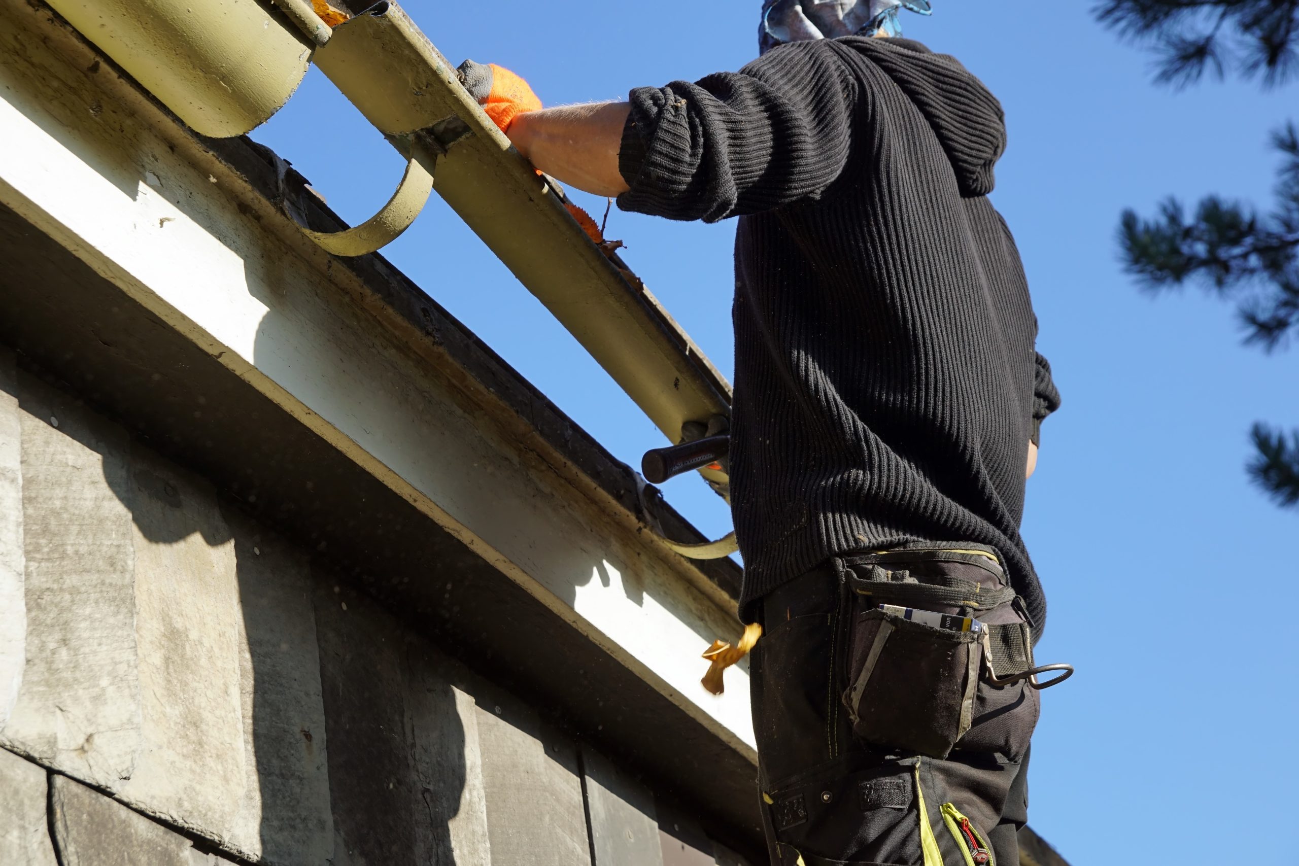 Low angle shot of a construction worker working and fixing a roof Average Roof Inspection Costs