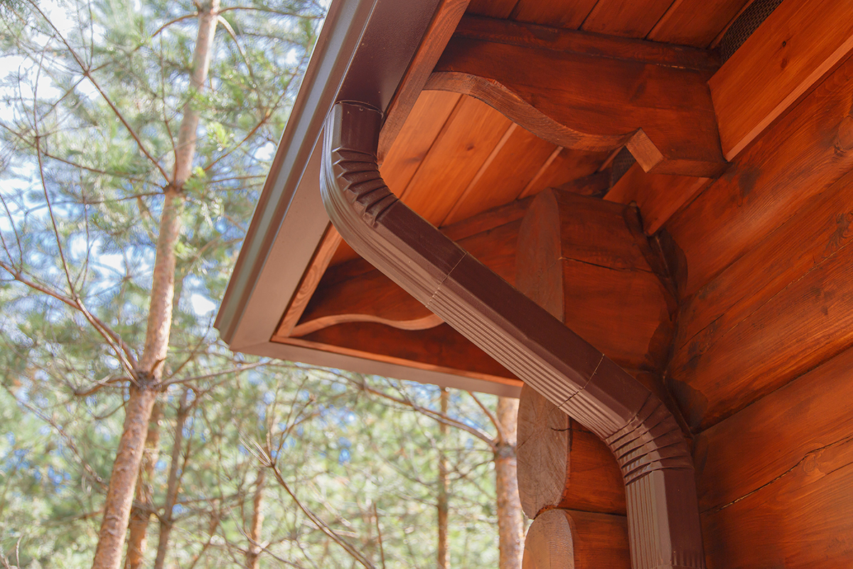 roof-gutter-system-on-log-house-in-forest-2022-12-16-21-41-26-utc-(2) Should gutters be installed before or after the new roof?